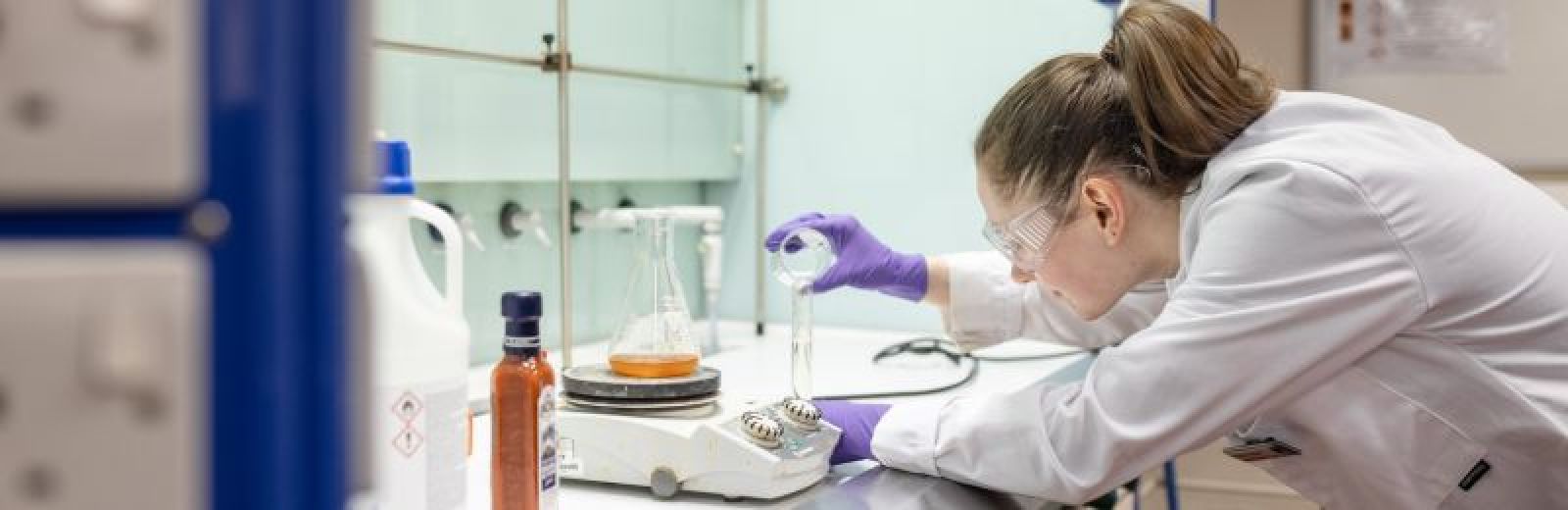A student performing an experiment in a fume cupboard.