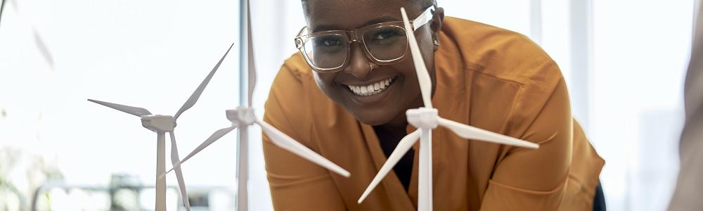 Person standing behind three model wind turbines.