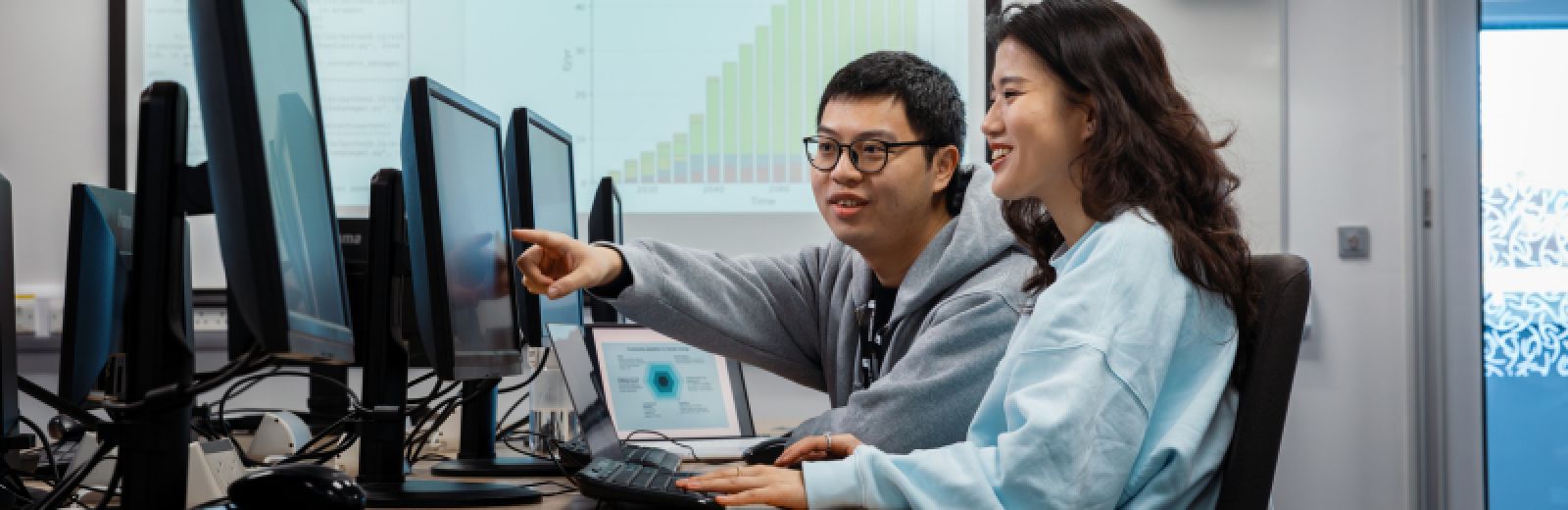 Students looking at computer screens and pointing at graphs
